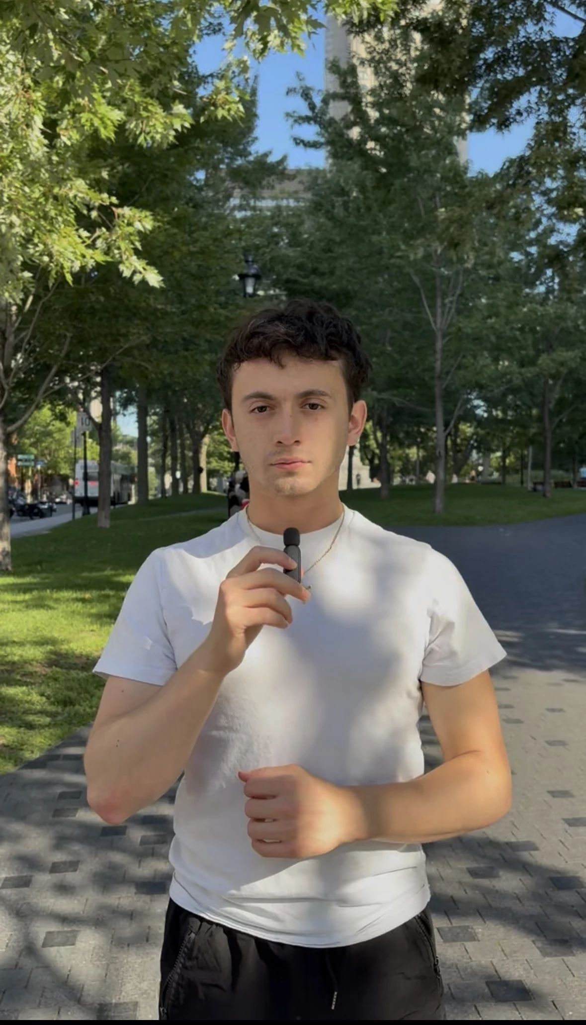 Justice holding a microphone on a tree-lined campus path