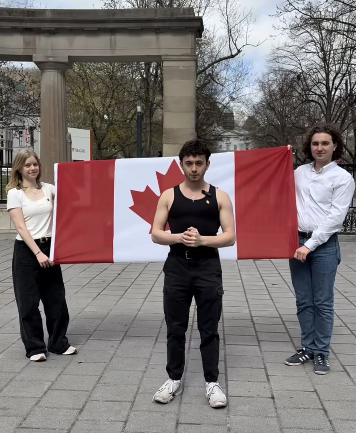 Justice speaking at campus gates with a Canadian flag
