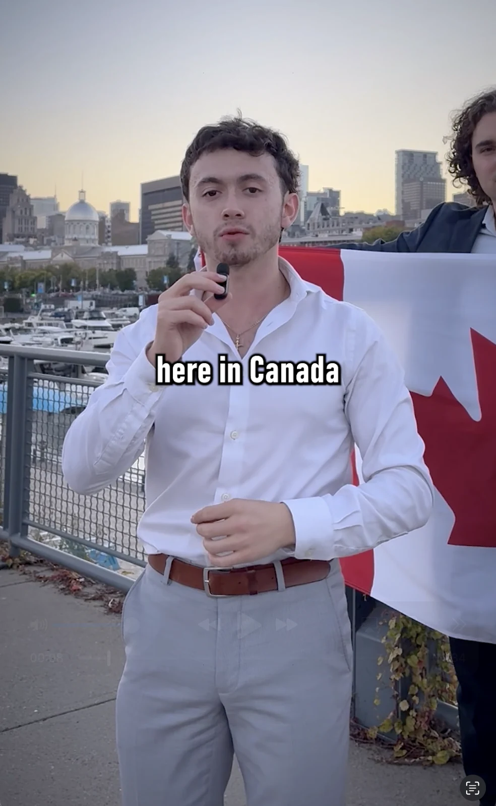 Justice holding a microphone with a Canadian flag behind him