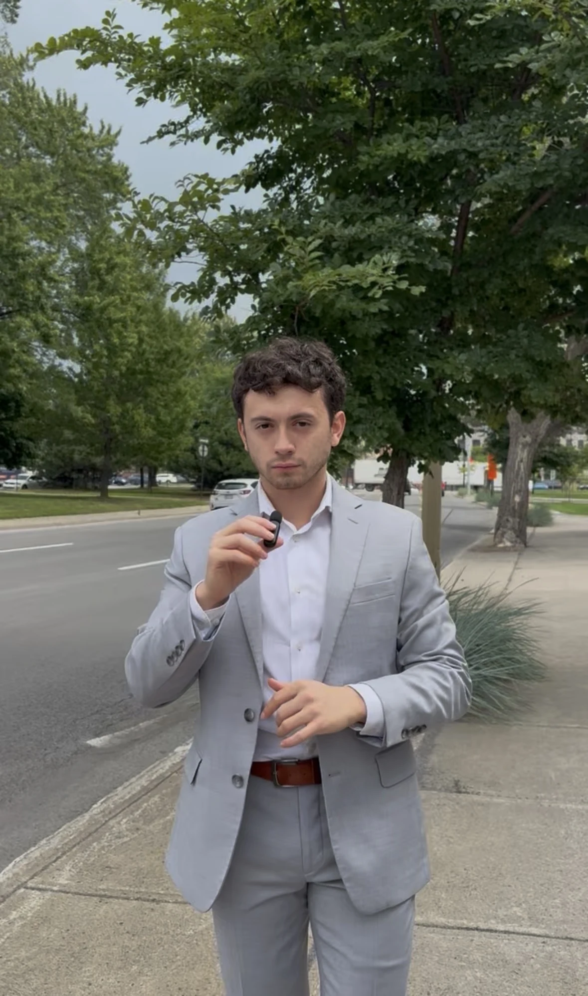 Justice speaking into a microphone in a light grey suit outdoors