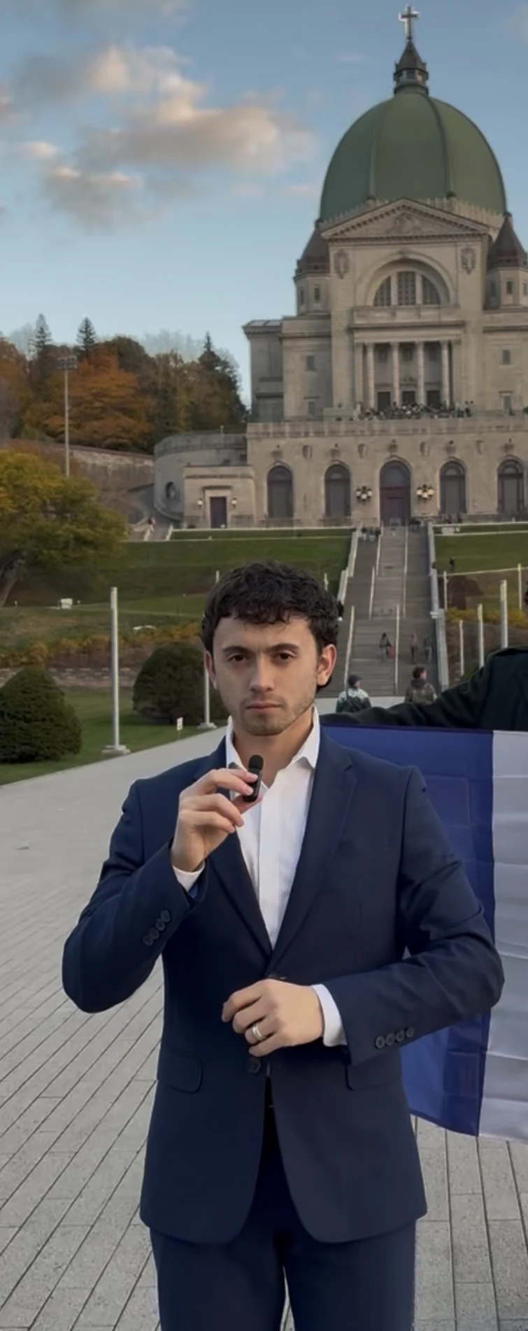 Justice holding a microphone in a navy suit outside a church