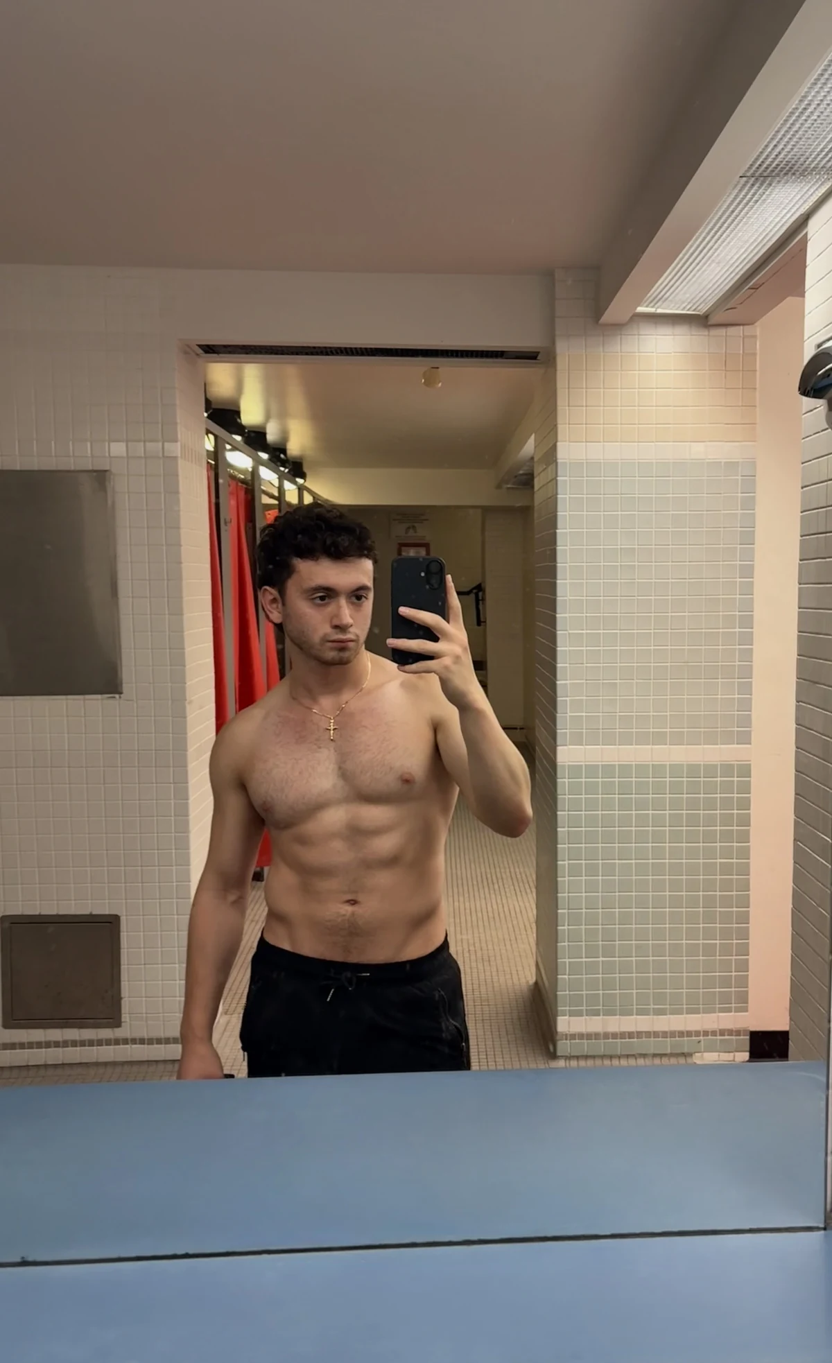 Justice taking a gym mirror photo while wearing a cross necklace